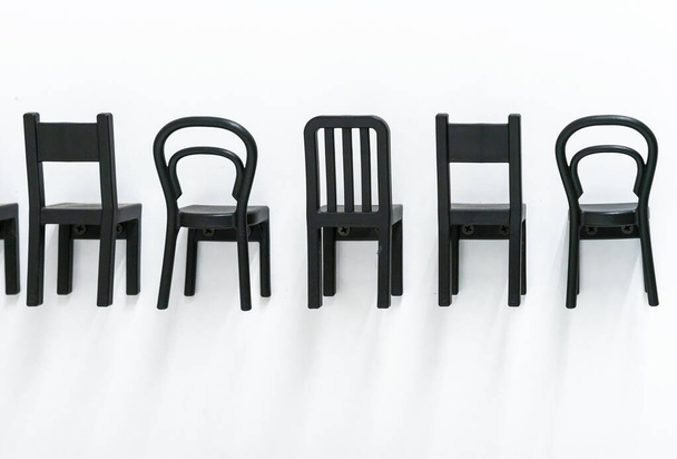 Siyah plastik sandalyeler beyaz duvara sabitlenir. Çocuk mobilyası konsepti. - Fotoğraf, Görsel