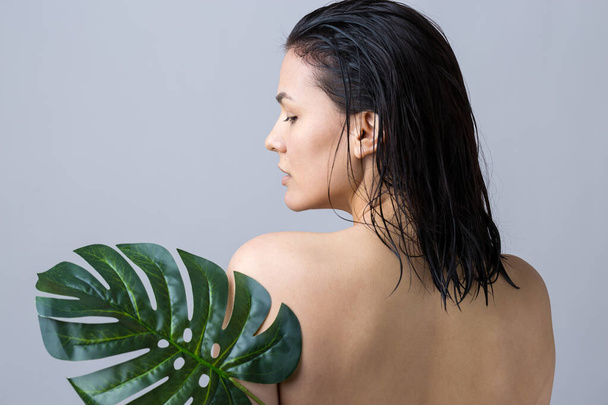 Doğal yeşil palmiye yaprağı portresi olan bir kadın. Moda, güzellik, makyaj, kozmetik. - Fotoğraf, Görsel