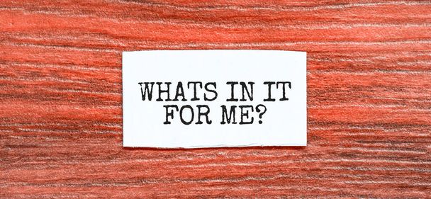 WHAT IS IN IT FOR ME text on the piece of paper on the red wood background - Foto, Imagen