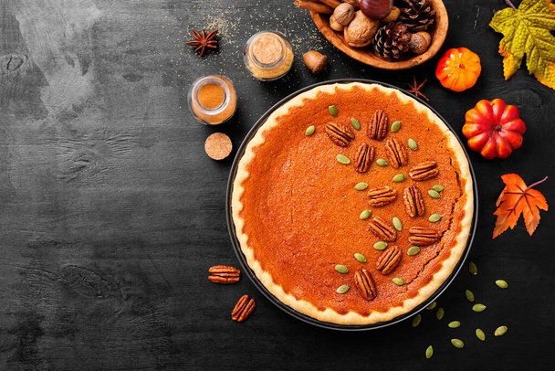 Festive Homemade Pumpkin Pie decorated with pecan nuts and pumpkin seeds. - 写真・画像