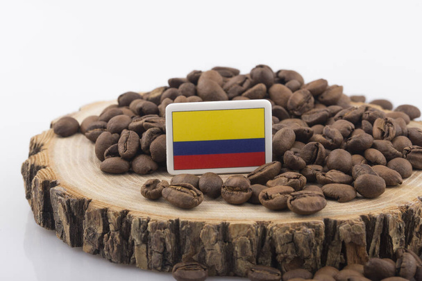 Kavrulmuş kahve çekirdeklerinin üzerine konmuş Kolombiya bayrağı. - Fotoğraf, Görsel