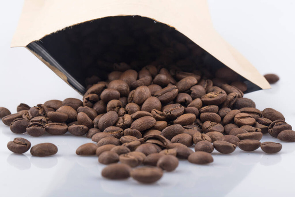 Χάρτινη σακούλα για καφέ με κόκκους καφέ που απομονώνεται σε λευκό φόντο - Φωτογραφία, εικόνα