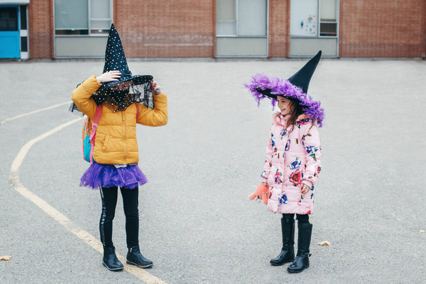Frohes Halloween. Freundinnen von Kindern in Kostümen und Gesichtsschutzmasken gehen zur Schule. Volksschüler feiern Halloween-Feiertag. Eine neue Normalität beim Coronavirus. - Foto, Bild