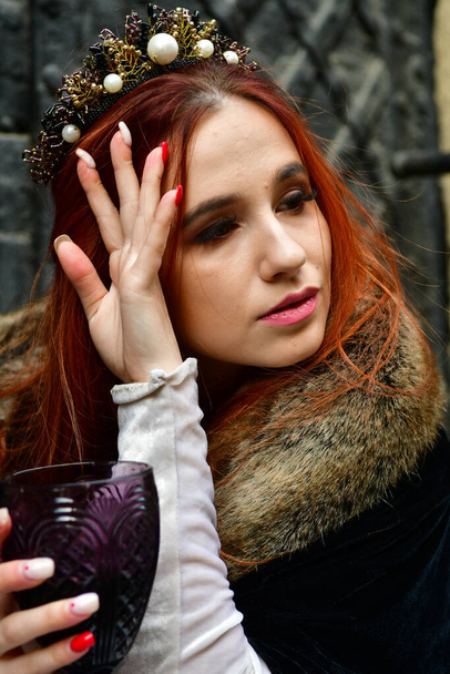 seksowna, długowłosa, młoda dziewczyna przed kamienną fortecą i metalowymi drzwiami z kieliszkiem wina w ręku - Zdjęcie, obraz