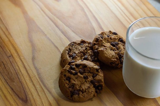 Ciasteczka czekoladowe i mleko na drewnianym stole - przestrzeń do kopiowania - Zdjęcie, obraz