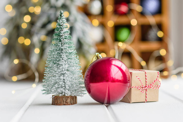 Schöne bunte Weihnachtsdekoration auf einem hellen Holztisch mit Girlanden und Weihnachtsbäumen im Hintergrund. Vorbereitung auf den Urlaub - Foto, Bild
