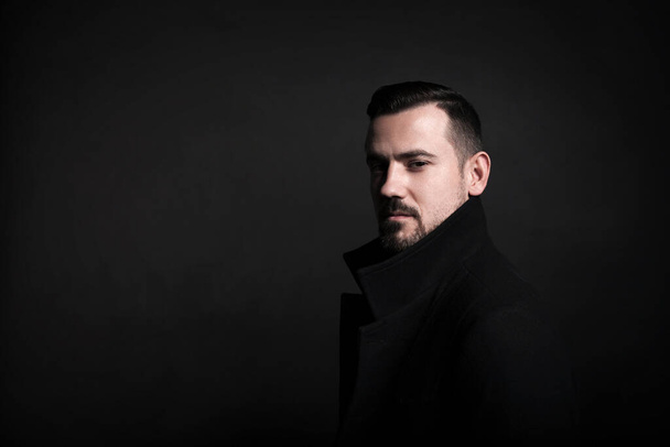 Portrait of a stylish young man in a black coat. Black background. - Foto, Bild