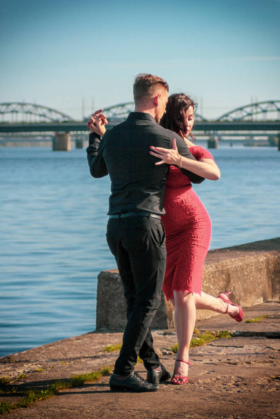 Young couple dancing together in the city. Cable-stayed bridge in the background. Selective focus. Portrait capture. - Фото, зображення