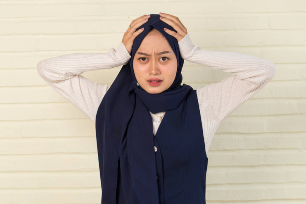 portrait of stressed sick muslim woman with headache; ill woman suffers from vertigo, dizziness, migraine, hangover, health care concept; young adult asian woman model - Foto, afbeelding