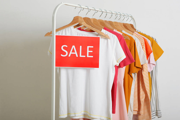 Одежда на перилах и табличка о продаже. Конечная продажа, скидки - Фото, изображение