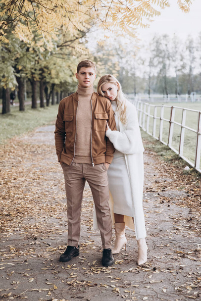 Beautiful young couple in autumn walks with dogs, pomeranian, in the park - Photo, Image