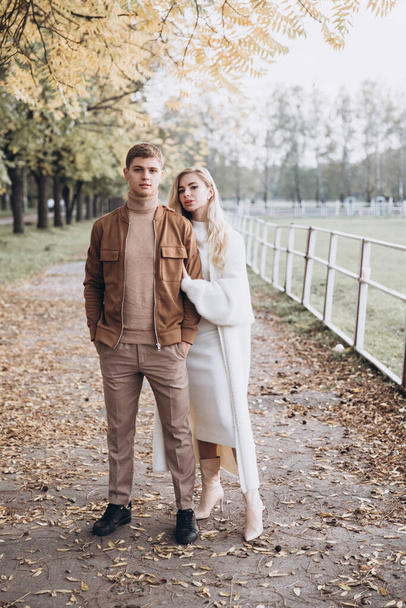 Beautiful young couple in autumn walks with dogs, pomeranian, in the park - Photo, Image