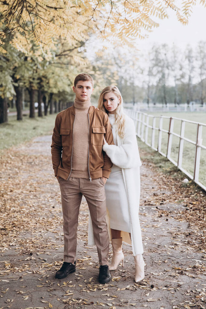 Beautiful young couple in autumn walks with dogs, pomeranian, in the park - Fotografie, Obrázek