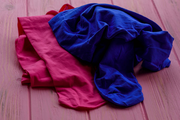 roze en blauwe maillot op houten ondergrond. roze en blauwe maillot als vrouwelijk kledingstuk. Kleding en weefsel - Foto, afbeelding
