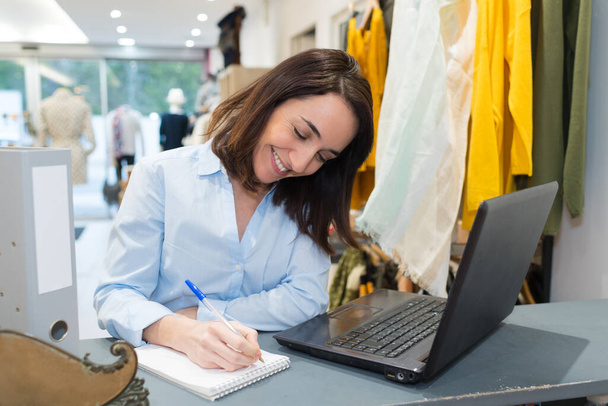 young woman with a laptop in her store - 写真・画像