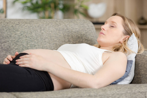sleepy pregnant woman lying on sofa at home - Zdjęcie, obraz