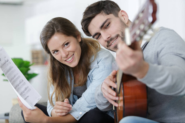 handsome man teaching girlfriend how to play the guitar - Photo, image