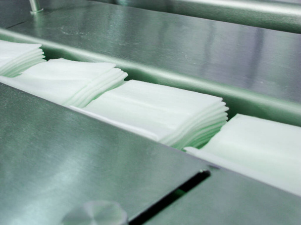 бытовые влажные салфетки для дезинфекции и чистки пропитанные антисептиком перемещения в конвейере на заводе - Фото, изображение