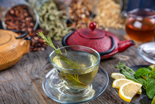 Vista aérea de varios tipos de té. Aromatizados con hierbas variadas, té de manzanilla, té de rosa mosqueta y salvia con una tetera y una taza de té.. - Foto, imagen