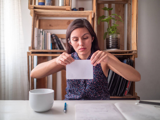 Egy fiatal spanyol nő egy íróasztalnál egy darab papírt hajtogat. - Fotó, kép