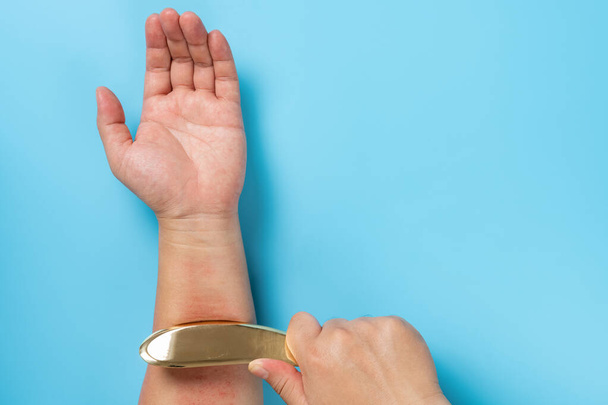 άνθρωπος ξύνοντας το χέρι του από μια γρατζουνιά χαλκού που είναι μια παραδοσιακή κινεζική ιατρική θεραπεία - Φωτογραφία, εικόνα