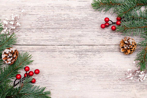 Kerst frame gemaakt van sparren takken, witte twijgen, rode bessen en kegels op de witte houten rustieke achtergrond.Kerst achtergrond.Kopieer ruimte voor tekst, bovenaanzicht, plat lay - Foto, afbeelding