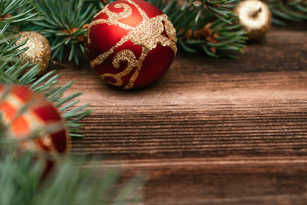 Christmas tree branches close up with red and gold balls on a dark wooden background.New Year,Christmas concept. Copy space for text,selective focus with shallow depth of field - Foto, afbeelding