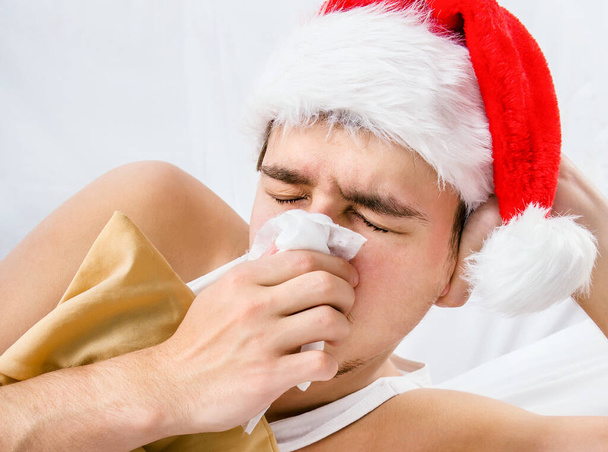 Sick Man in Santa Hat with a Handkerchief in the Bed closeup - Foto, Imagen