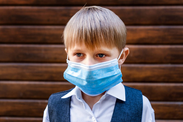Sad Kid in a Flu Mask on the Wooden Wall Background - Фото, зображення