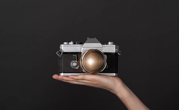 Hand holding the vintage camera on the black background. - Photo, Image