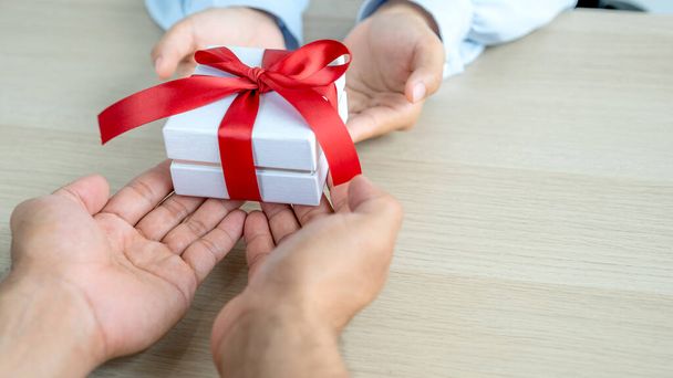 Κουτί δώρων στα χέρια, τα χέρια των ανδρών δίνουν δώρα στα χέρια των γυναικών στο φεστιβάλ των ειδικών διακοπών, όπως τα Χριστούγεννα, την Πρωτοχρονιά ή την Ημέρα του Αγίου Βαλεντίνου. - Φωτογραφία, εικόνα