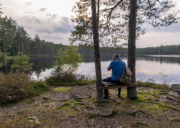 silhouette of a sitting man on a bench by the bog lake, bog lake landscape, autumn time - Φωτογραφία, εικόνα