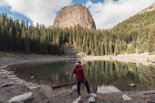 Uomo fotografo in piedi su Mirror Lake nella foresta autunnale vicino al lago Louise a Banff parco nazionale, Canada - Foto, immagini