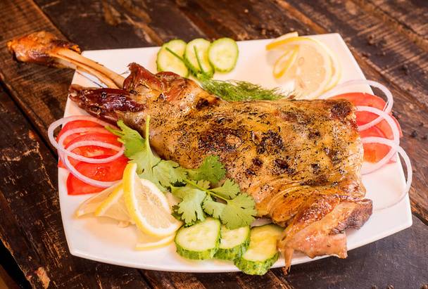 grilled large leg lamb lying on a wooden table - Foto, imagen
