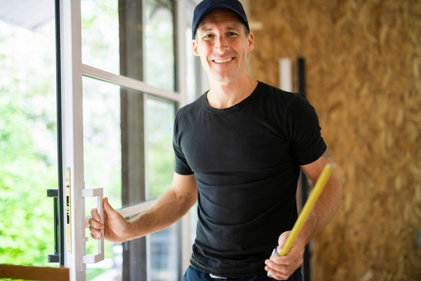 A handsome young man installing Double Sliding Patio Door in a new house construction site - Photo, image
