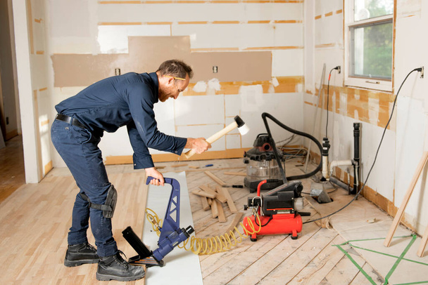 Ein männlicher Arbeiter verlegt Holzboden auf einem Haus - Foto, Bild