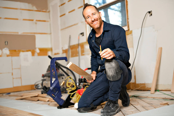 A Male Worker install wood floor on a house - Zdjęcie, obraz