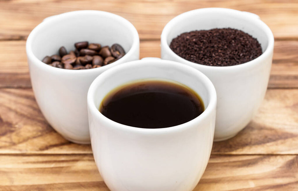 Kubki z napojem kawowym, mieloną kawą i fasolą na drewnianym stole. - Zdjęcie, obraz