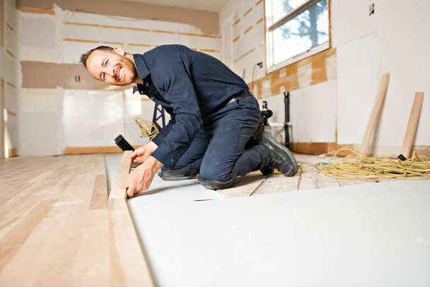 A Male Worker install wood floor on a house - Фото, зображення
