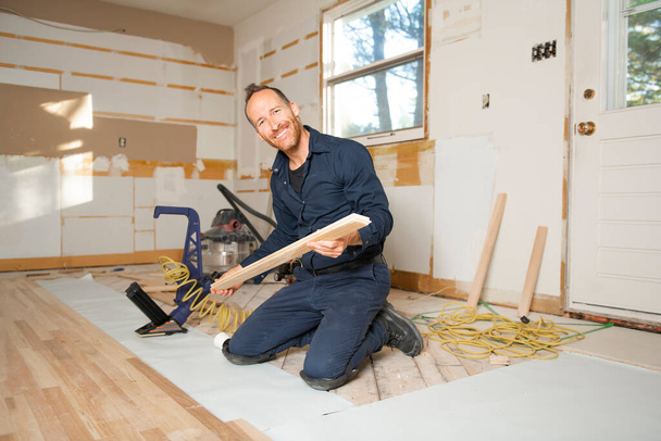 A Male Worker install wood floor on a house - Foto, afbeelding