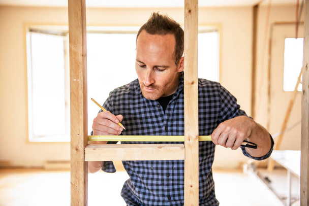 A man worker in the carpenter workroom renovation using tape - Фото, зображення