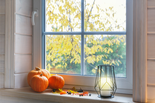 Citrouilles orange sur le rebord de la fenêtre, bougies, feuilles d'automne, lanterne. Style scandinave. - Photo, image