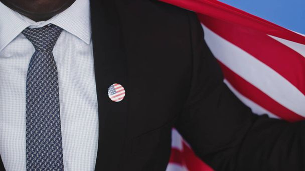 unrecognizable young african american black man in formalwear with usa badge on the chest holding usa flag - Photo, Image