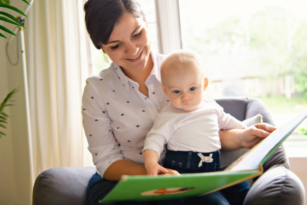 happy loving family. pretty young mother reading a book to baby - Foto, afbeelding