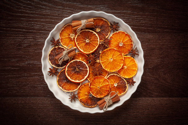 Christmas - natural Christmas decorations on a white plate - dried oranges, and cinnamon - Photo, Image