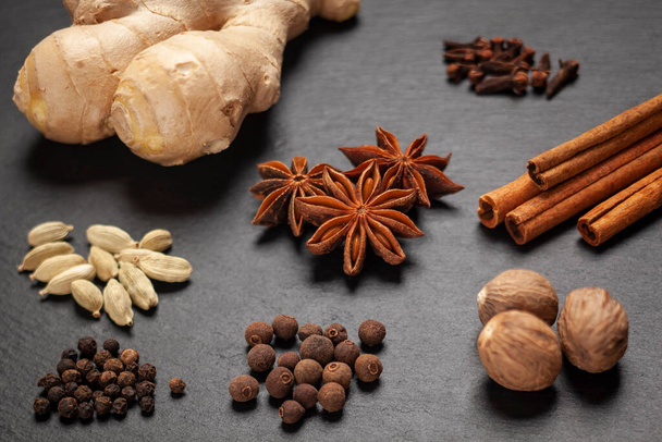 Gingerbread spices on slate - star anise, cinnamon, cloves, nutmeg, ginger, cardamom, black pepper, allspice - Photo, Image