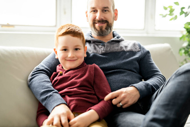 Father with redhead child sit on the sofa at home - Φωτογραφία, εικόνα