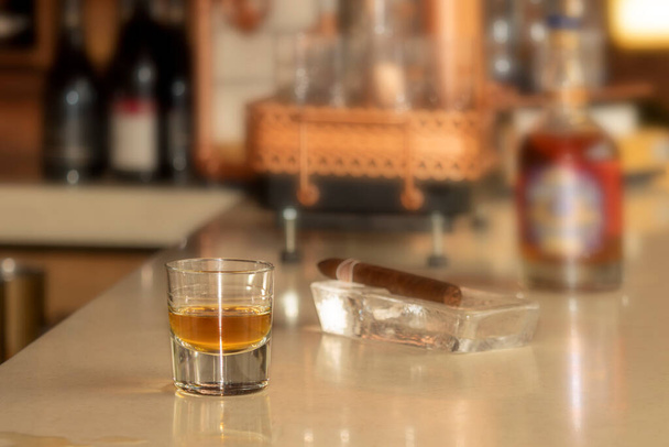 Bar masasında duran viski bardağı ve puro. - Fotoğraf, Görsel