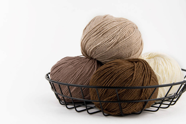 Balls of yarn for knitting brown flowers in a metal basket on a white background. - Φωτογραφία, εικόνα