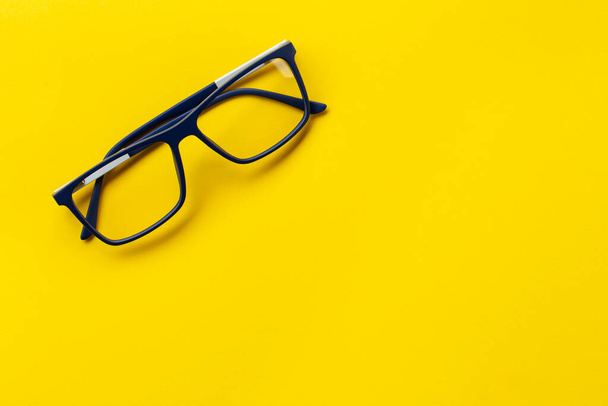 Модные очки в синих рамках для зрения на желтом фоне. Концепция здоровья. Медицинская область, которая изучает глаза. - Фото, изображение